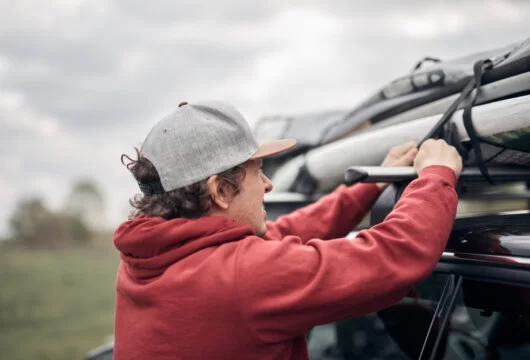 Man loading gear onto the roof rack of his rental car
