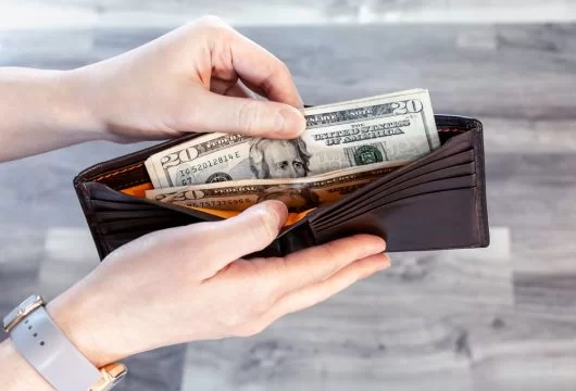 Person holding wallet with cash after cashing a check