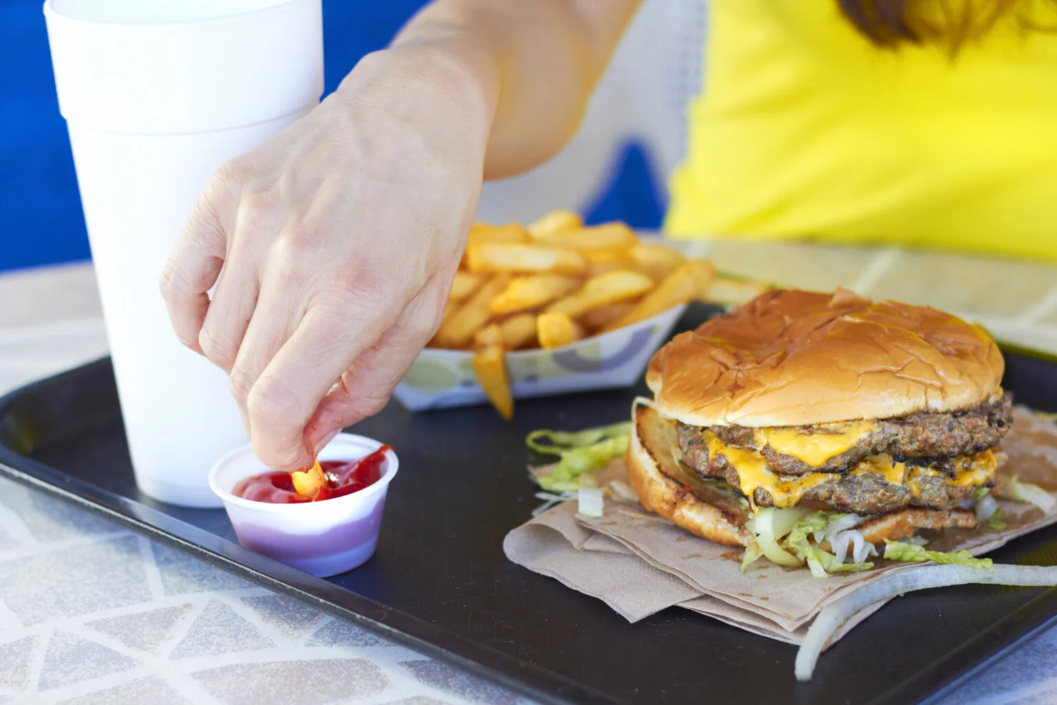 Person eating a burger and fries at a fast food place that takes EBT