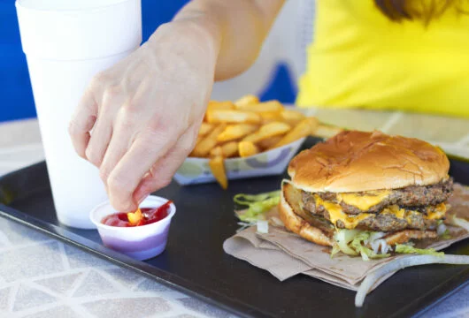 Person eating a burger and fries at a fast food place that takes EBT