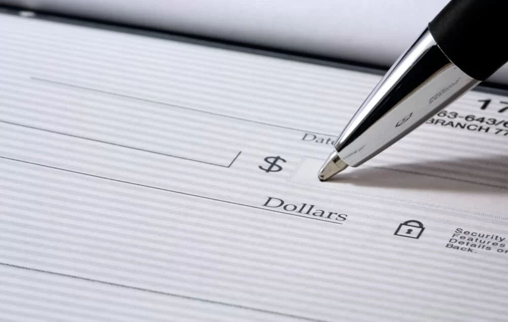 Silver pen tip writing the dollar amount on a check