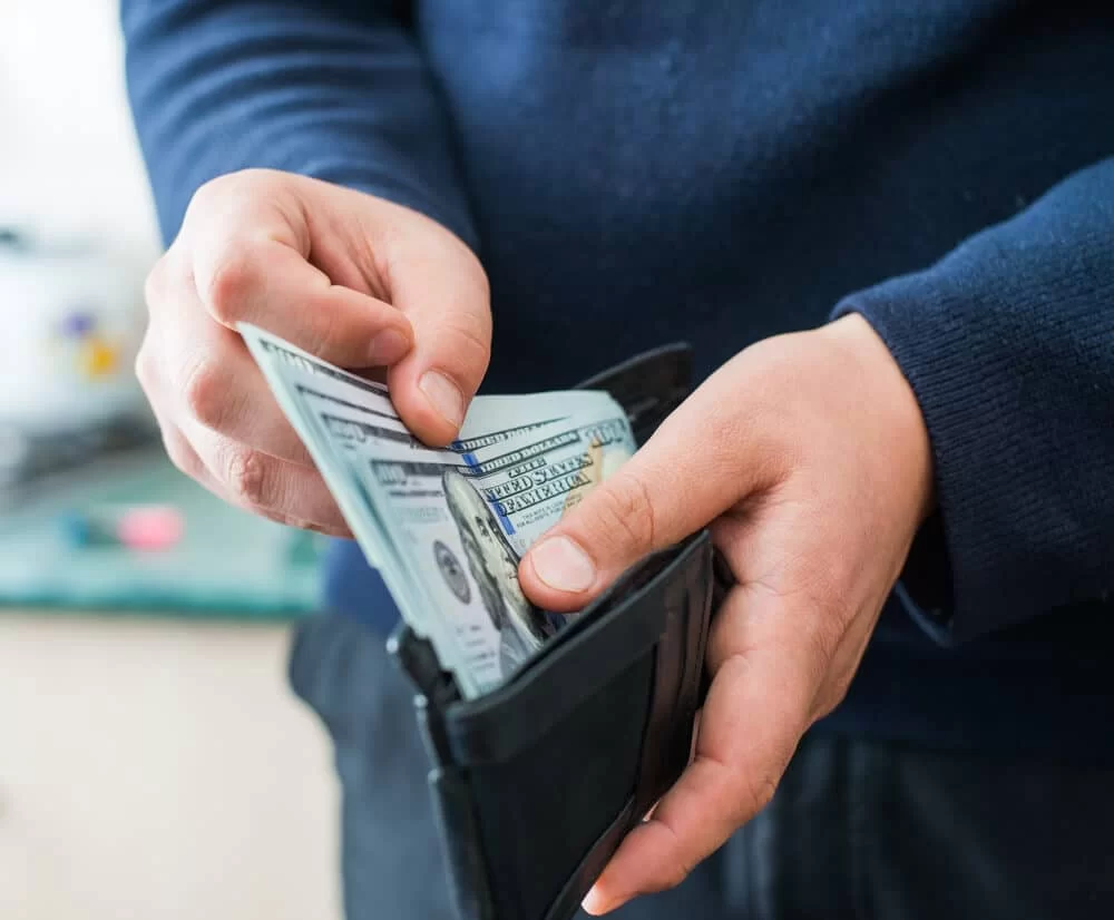 Man removing cash from wallet to pay for a money order