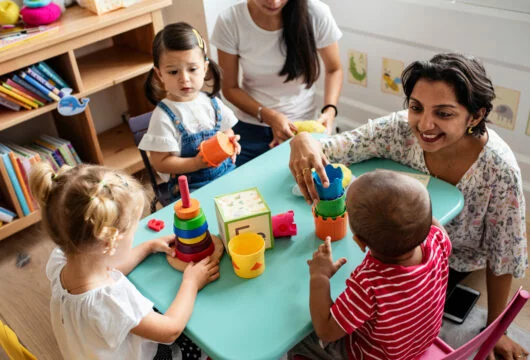 Children doing an activity with a teacher at a school like Kiddie Academy