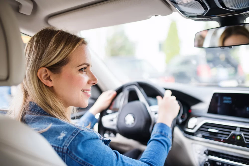 Young woman driving a car rented with cash only