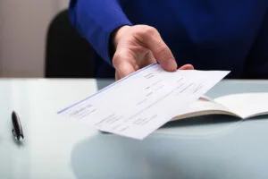Close-up of a person's hand holding a check
