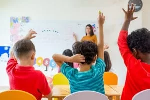 Children raising their hands to answer a question at school