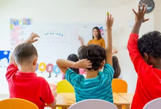 Children raising their hands to answer a question at school