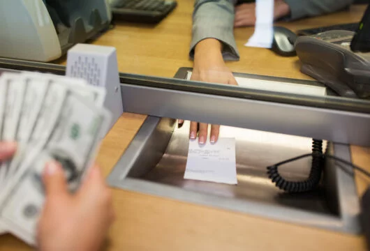 Teller passing a receipt to a customer after cashing a cashier's check