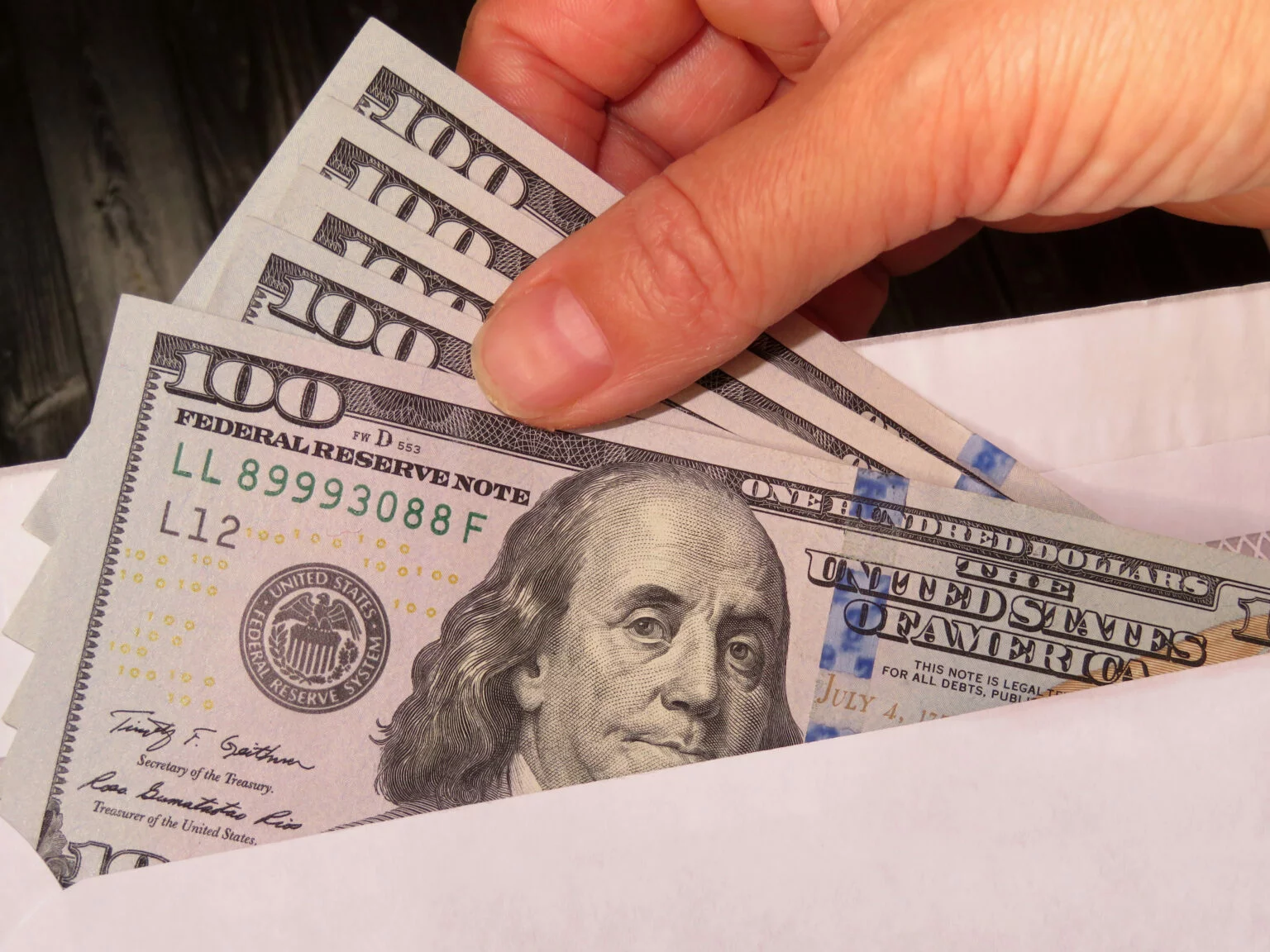 Person putting cash in an envelope after cashing a starter check