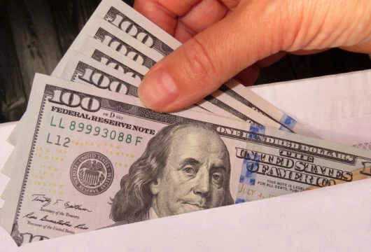 Person putting cash in an envelope after cashing a starter check