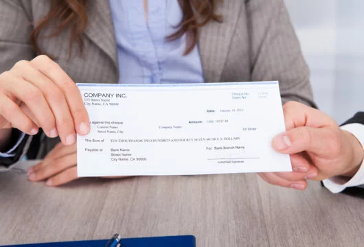 Woman and man holding a sample third-party check