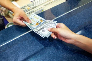 Close-up of a teller handing cash to someone after cashing a two-party check
