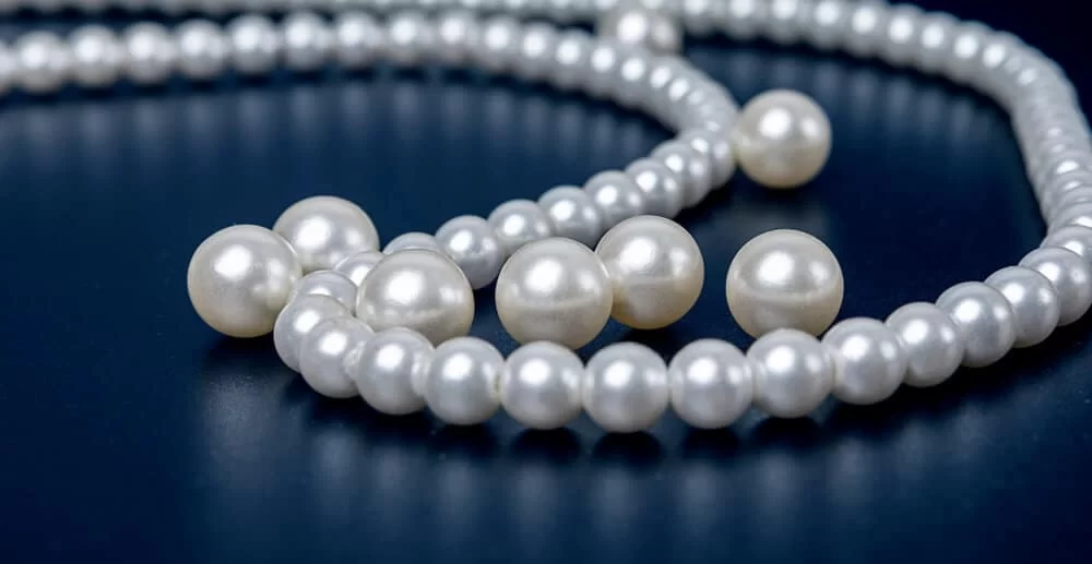 Loose and strand pearls resting on a dark table