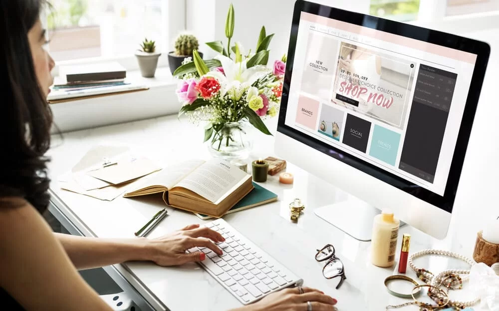woman shopping online, with books and paper on her desk