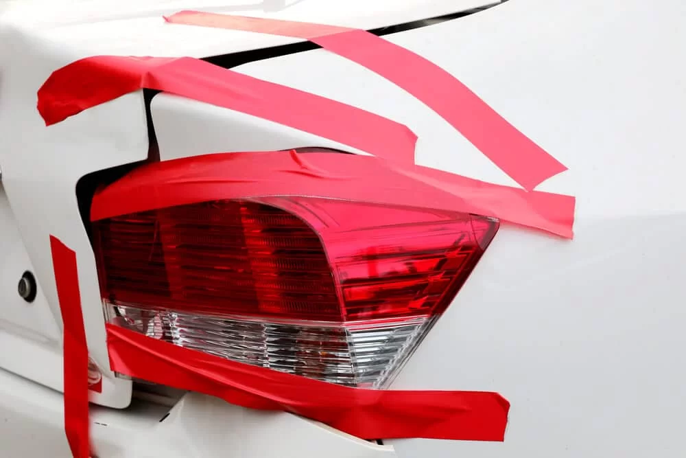 Picture of a car with light rear quarter panel damage and red duct tape over a tail light.