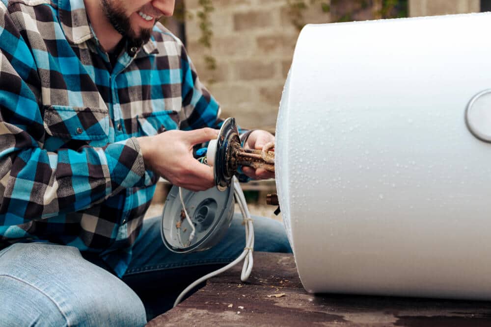 Man taking apart an old water heater for scrap