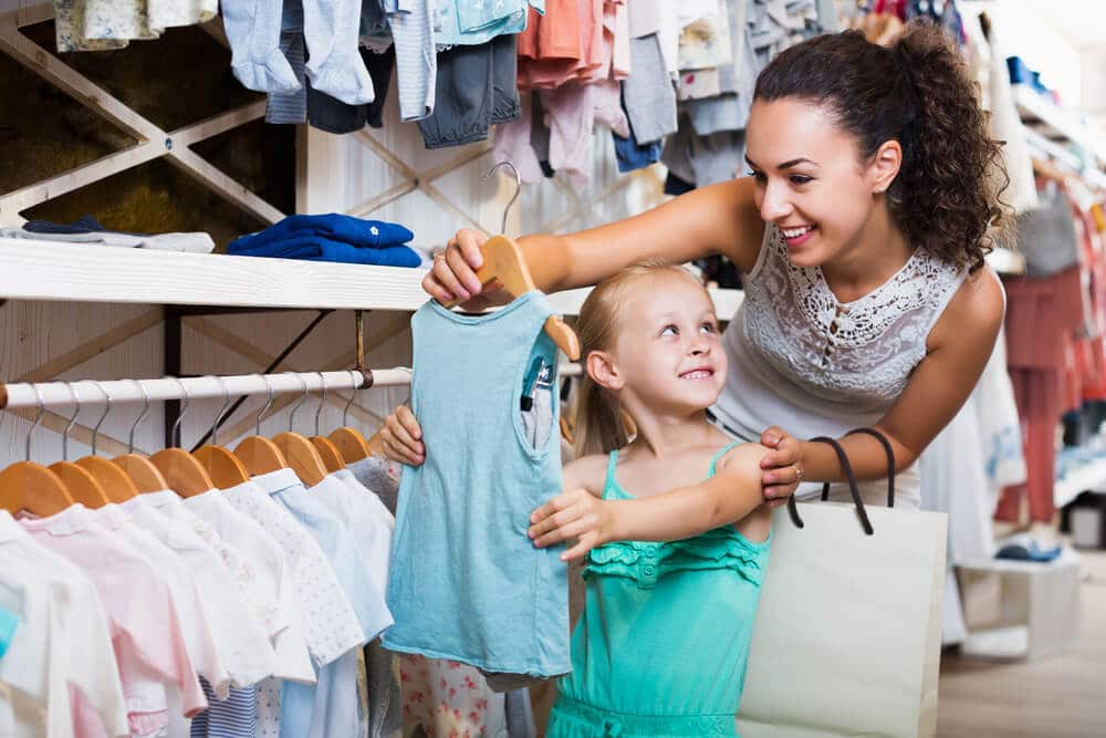 Young mother shopping at a buy now, pay later kids store with her daughter