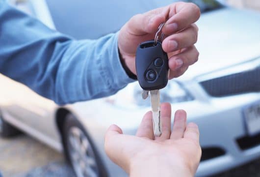 Person handing a rental car key to someone else