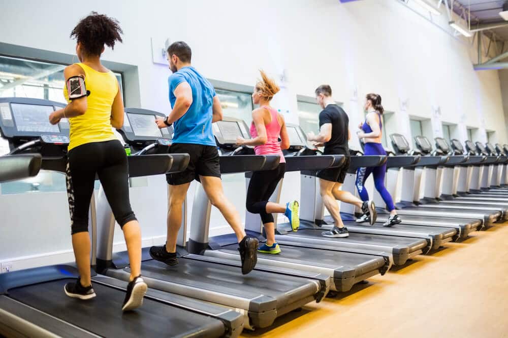 A group of people using treadmills at a gym