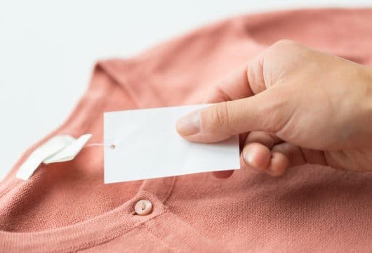 Close-up of woman's hand holding an attached clothing tag