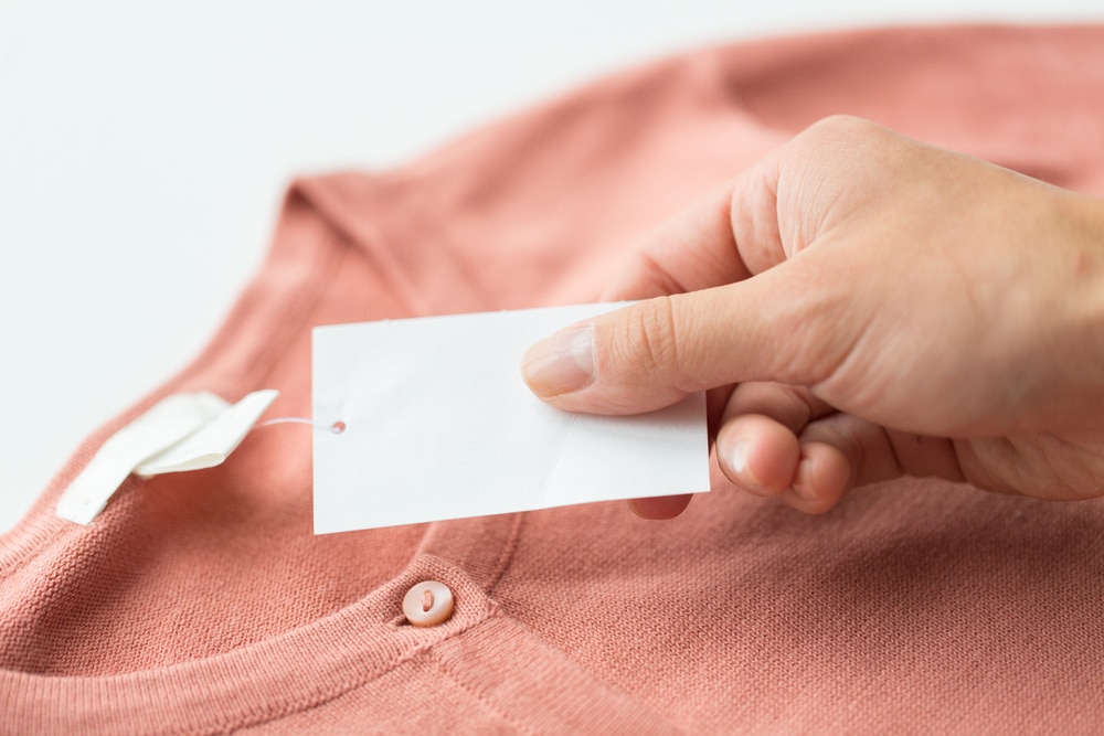 Close-up of woman's hand holding an attached clothing tag