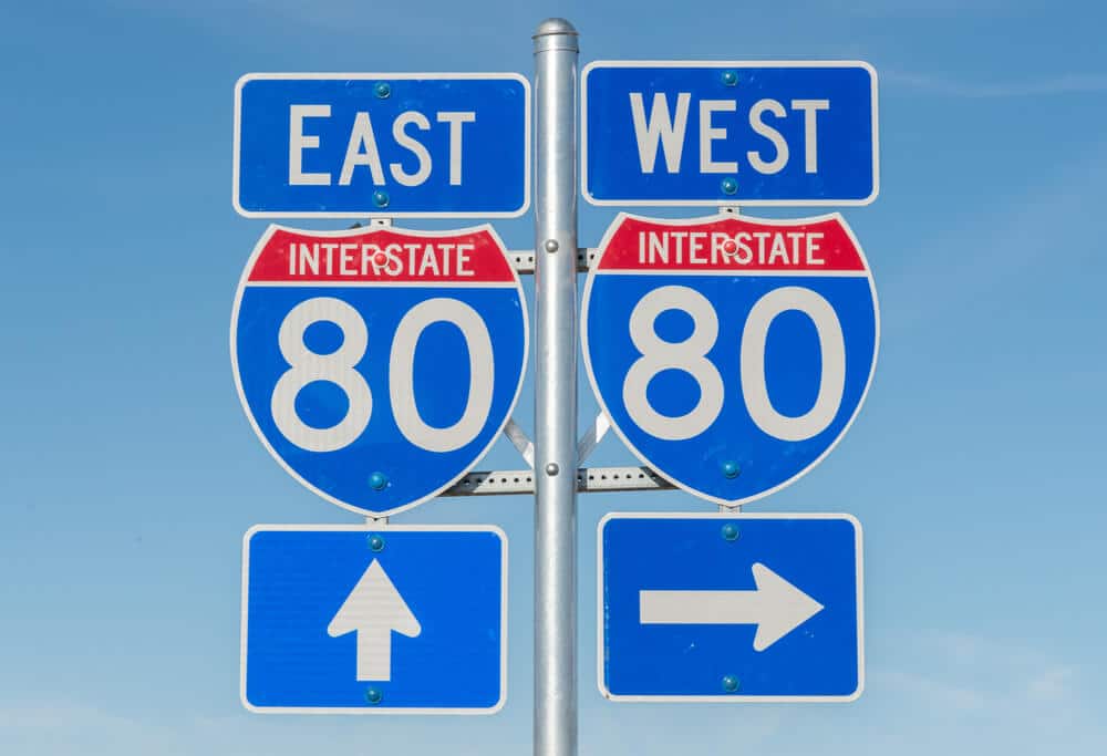 A road sign that points to an interstate going east and an interstate going west.