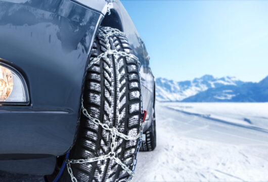 Close-up of a rental car tire with snow chains