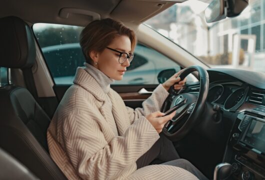 Woman checking her phone in a car rented with PayPal
