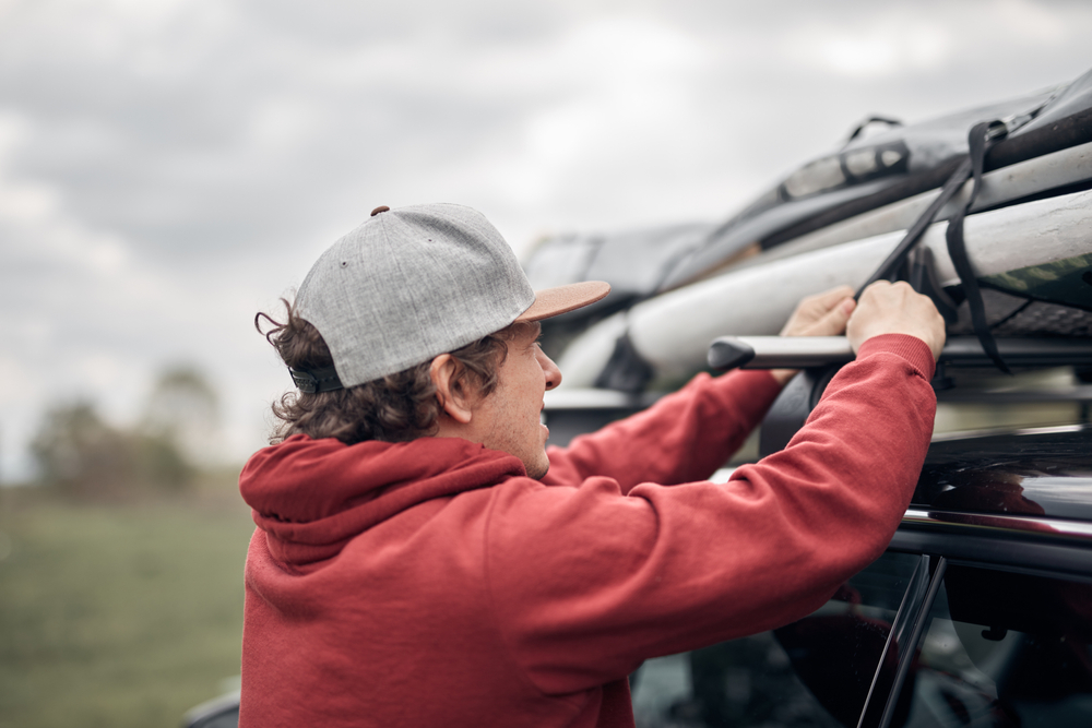 Man loading gear onto the roof rack of his rental car