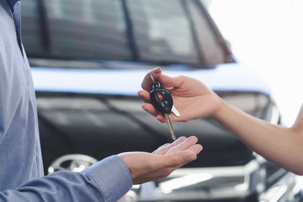 Car rental employee passing keys to a renter