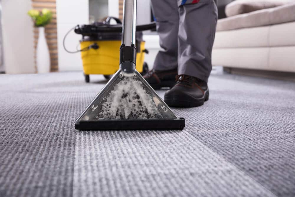 Man using a carpet cleaner on a dirty rug