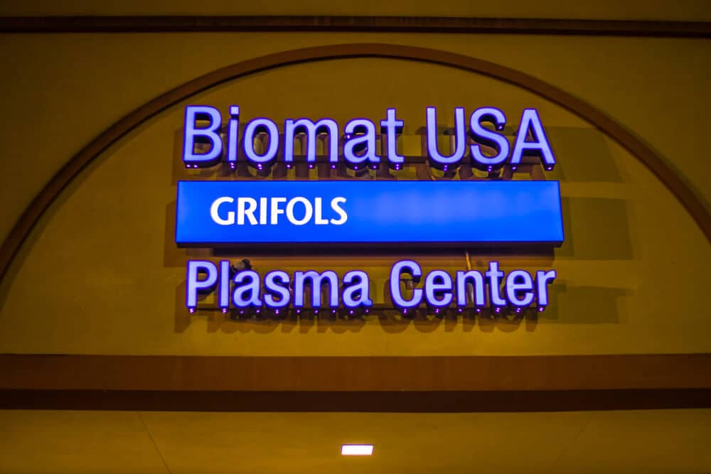 Sign reading "Biomat USA Grifols Plasma Center" on the outside of a plasma donation center