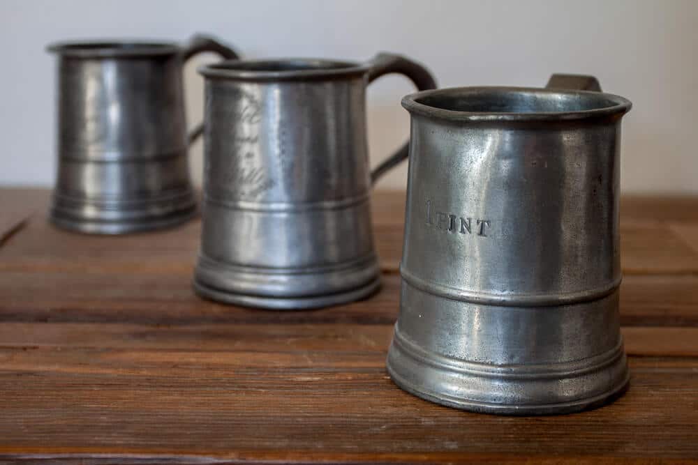 Three pewter mugs on a wooden table