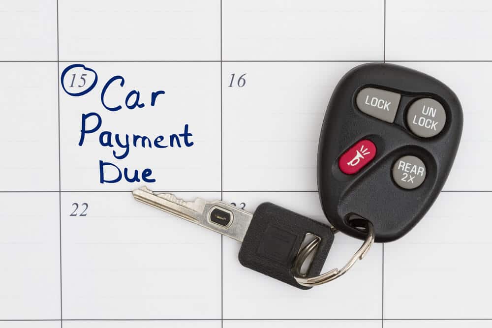 Car key resting on calendar with car payment due date