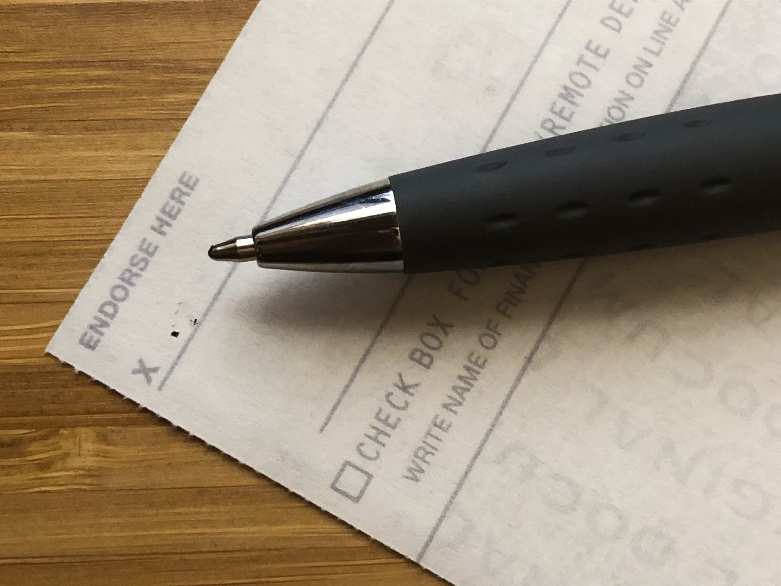 Pen resting on the back of a check at the "Endorse Here" line