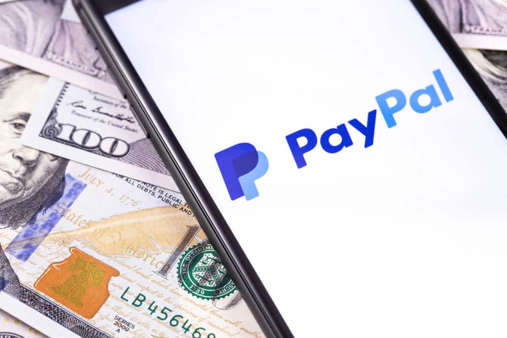 Phone loading the PayPal app on top of $100 bills
