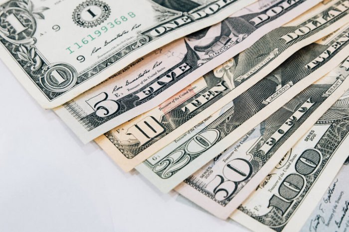 Side income money earned laying on a table from a $1 bill to a $100 bill.