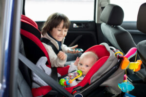 Baby and toddler in a rental car buckled into a car seat and booster seat