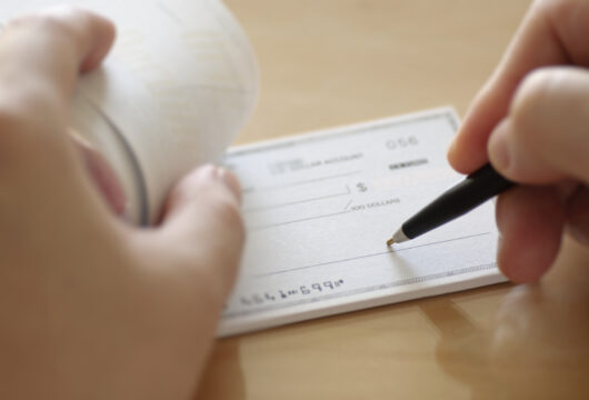 Close-up of a person filling out a personal check