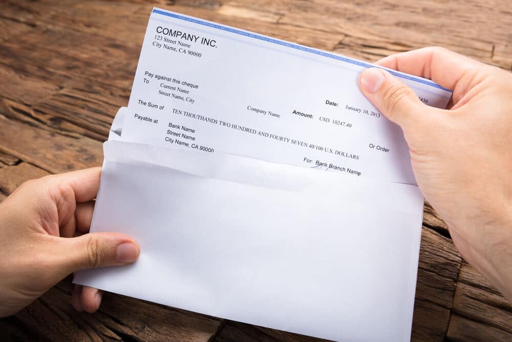 Hands removing a check from an envelope to cash it
