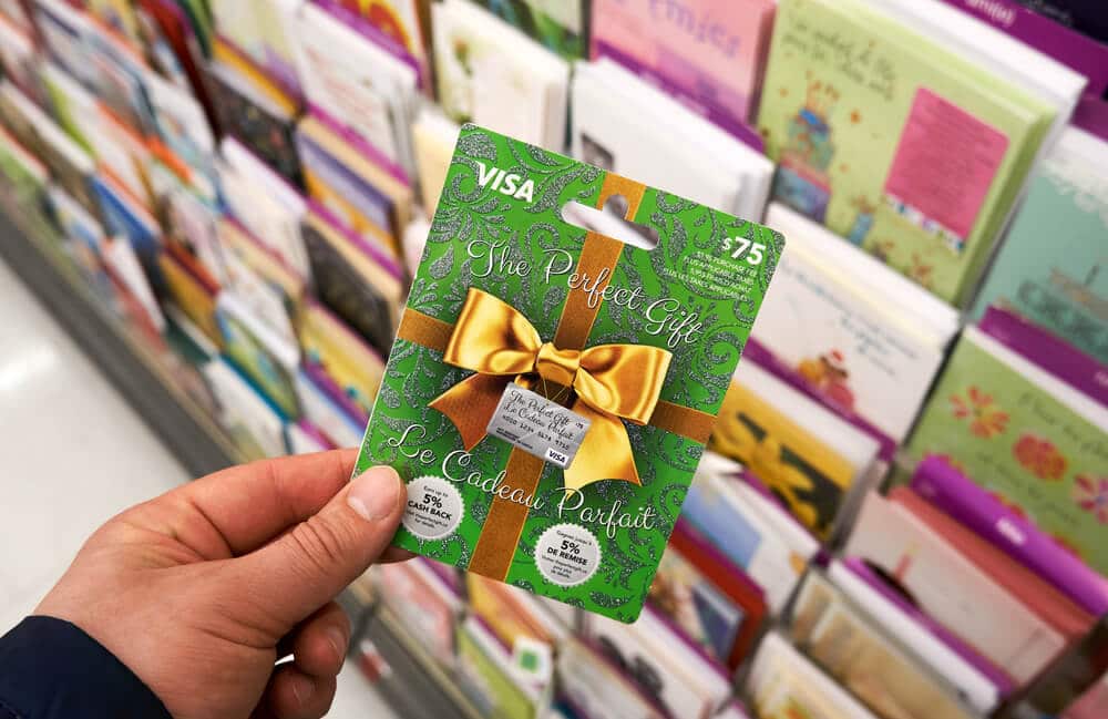 Hand holding a Visa gift card in the greeting card aisle of a store