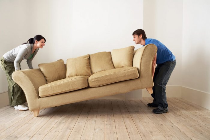 A man and woman move a used couch.
