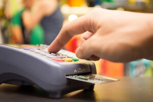 Close-up of a person's hand selecting a button on a credit card reader