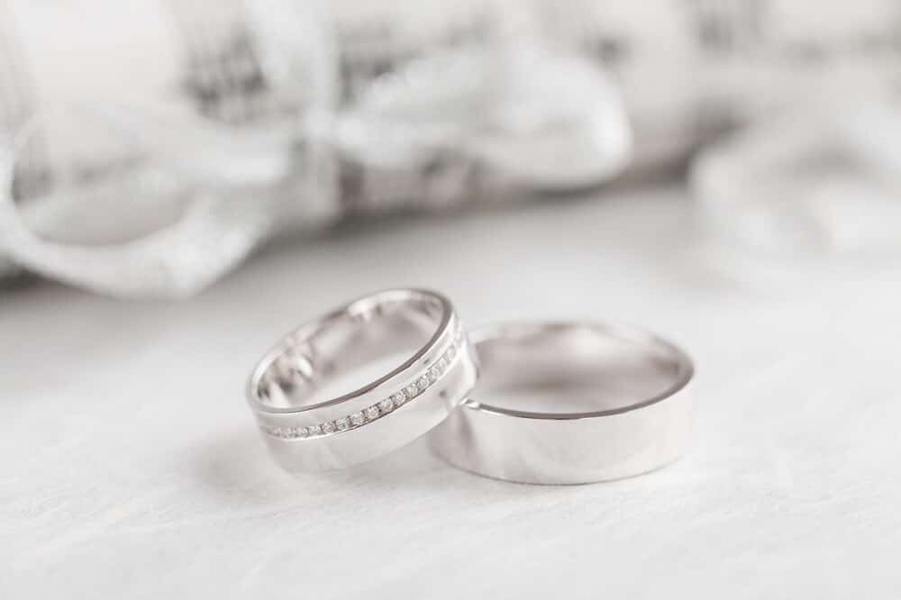 Two white gold rings resting on a white table