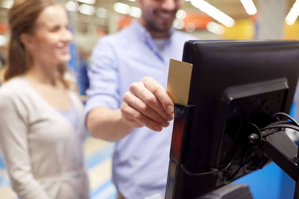 man slides card at self-checkout register
