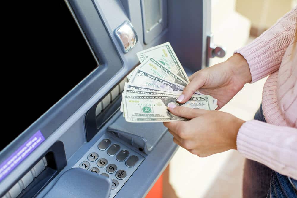 woman's hands holding cash received after cashing a check at an ATM