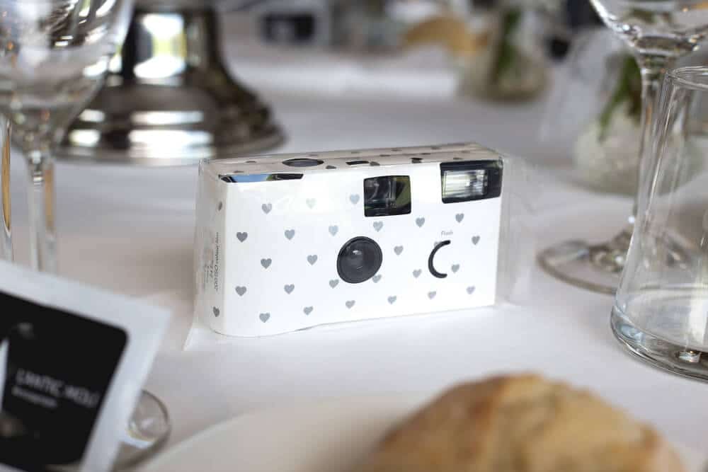 A disposable camera sitting on a table at a wedding reception.