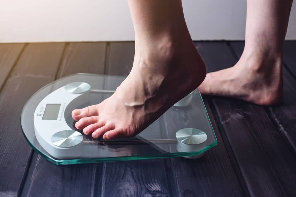 person stepping on a glass scale